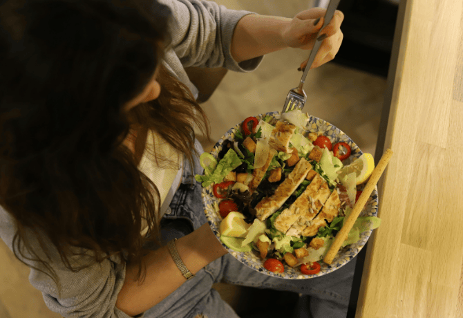 mujer joven sujetando un plato con una ensalada cesar