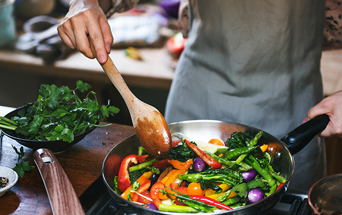 11_DietaSaludable.png persona cocinando verduras en una sarten