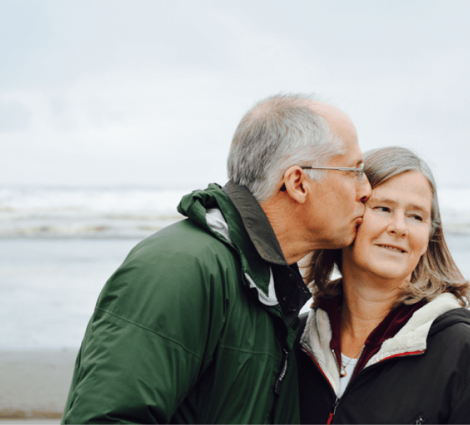 Elderly man kissing his wife on the cheek